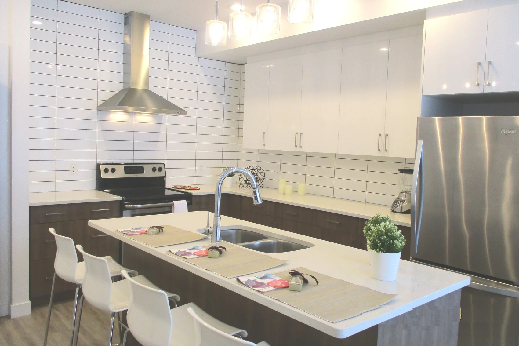 Bright kitchen in the Edmonton house with an island, bar stools and a stainless steel fridge