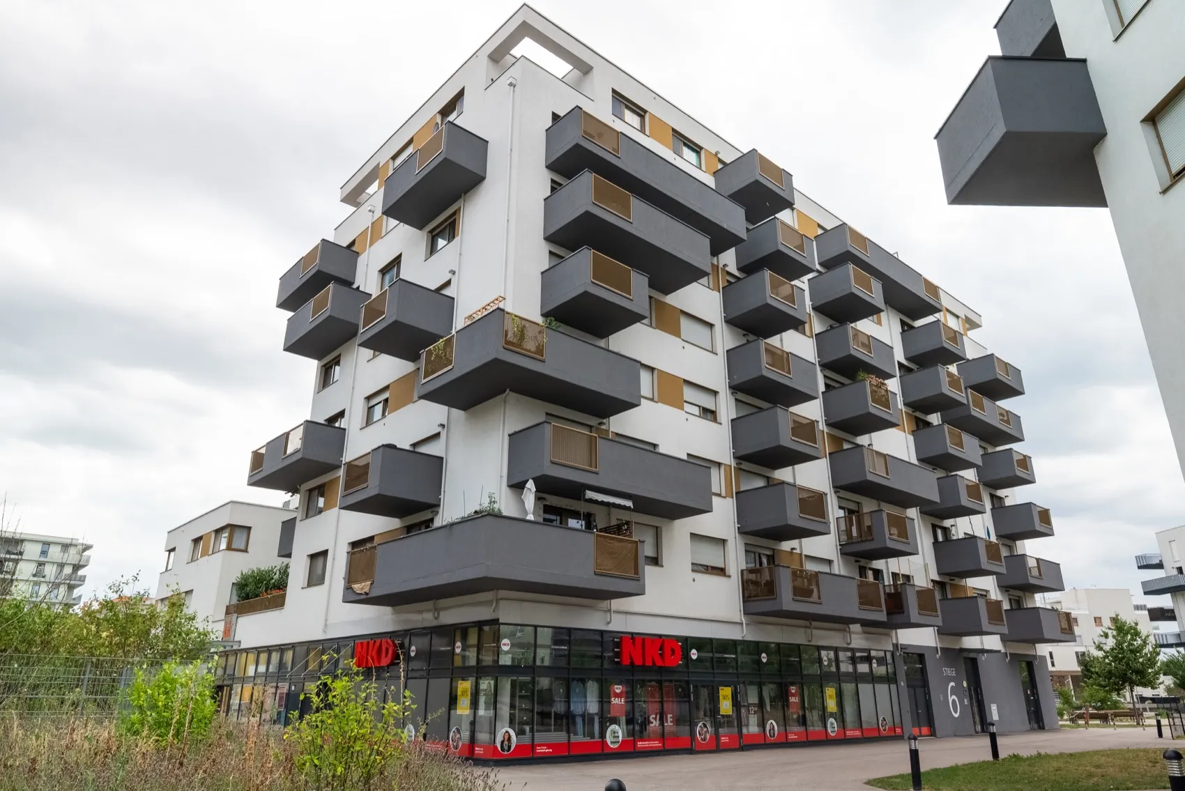 Modern apartment building at Stadlauer Strasse 64 in Vienna with planted balconies, corner view