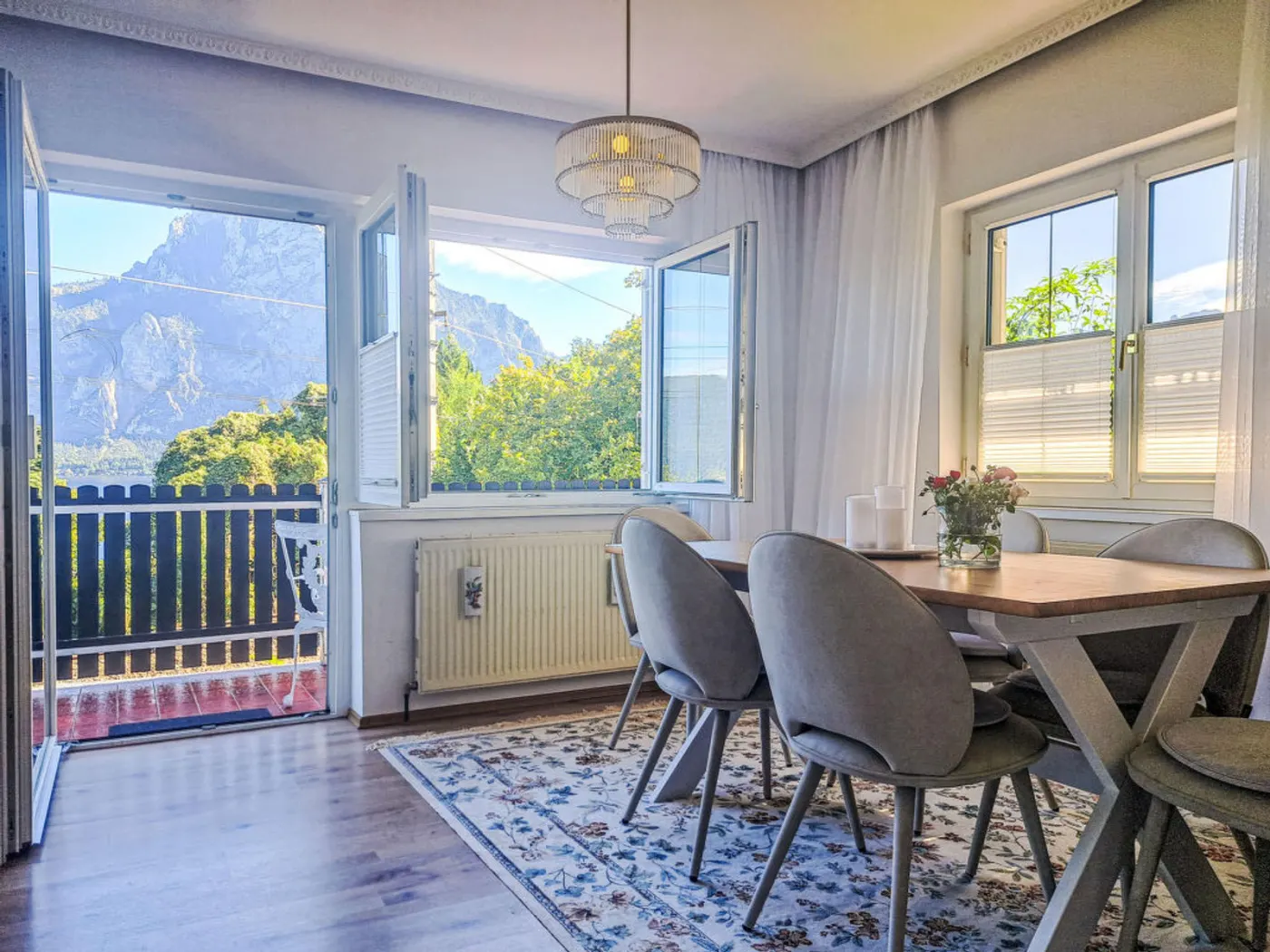 Dining area of Villa Rose with an open balcony door and a view of the Traunstein